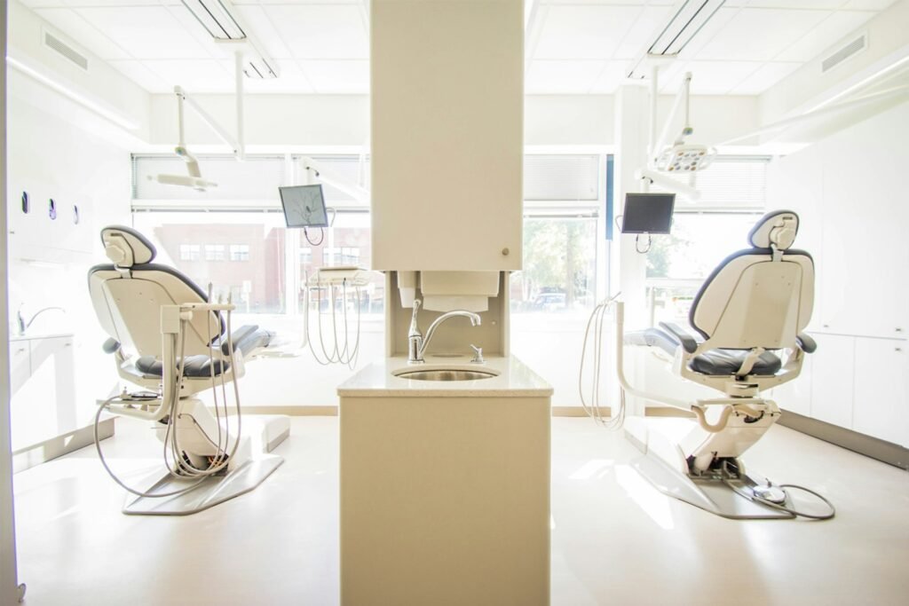 Sala clinica odontologica clara com duas cadeiras e equipamentos posicionados lado a lado