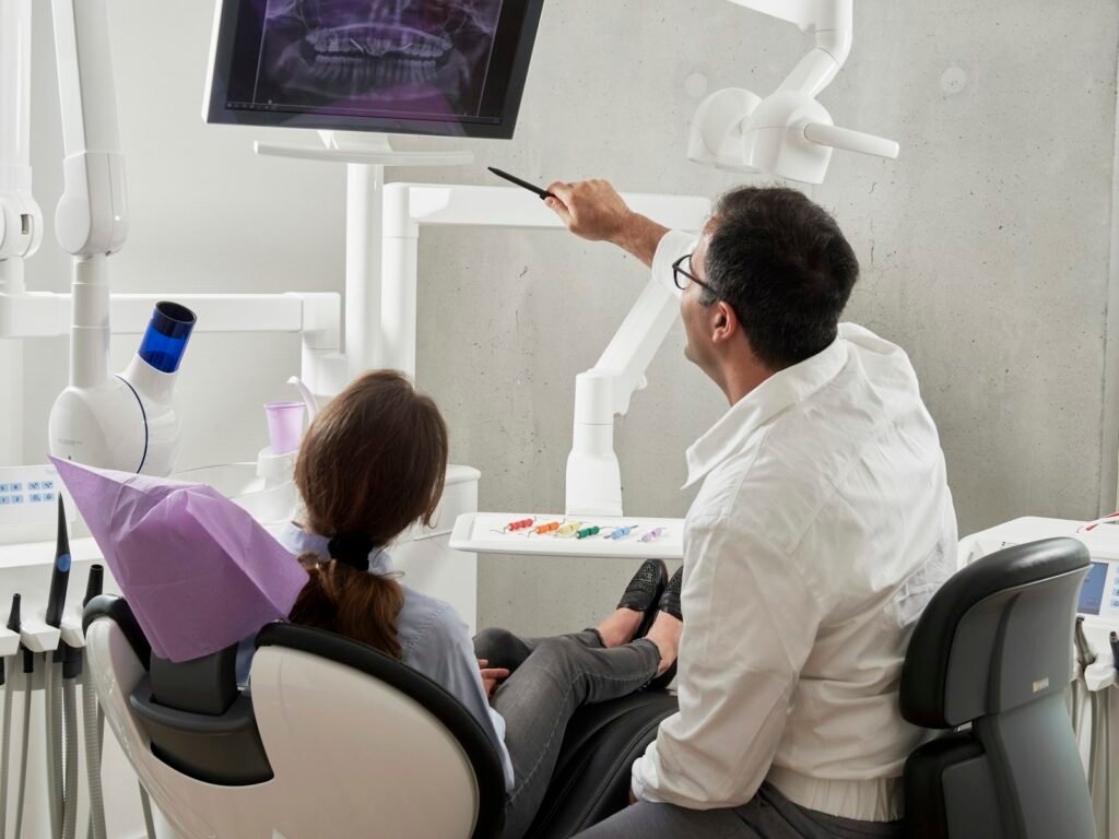 Dentista apresentando uma radiografia odontologica na tela durante o atendimento de um paciente