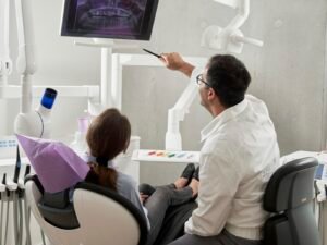 Dentista apresentando uma radiografia odontologica na tela durante o atendimento de um paciente